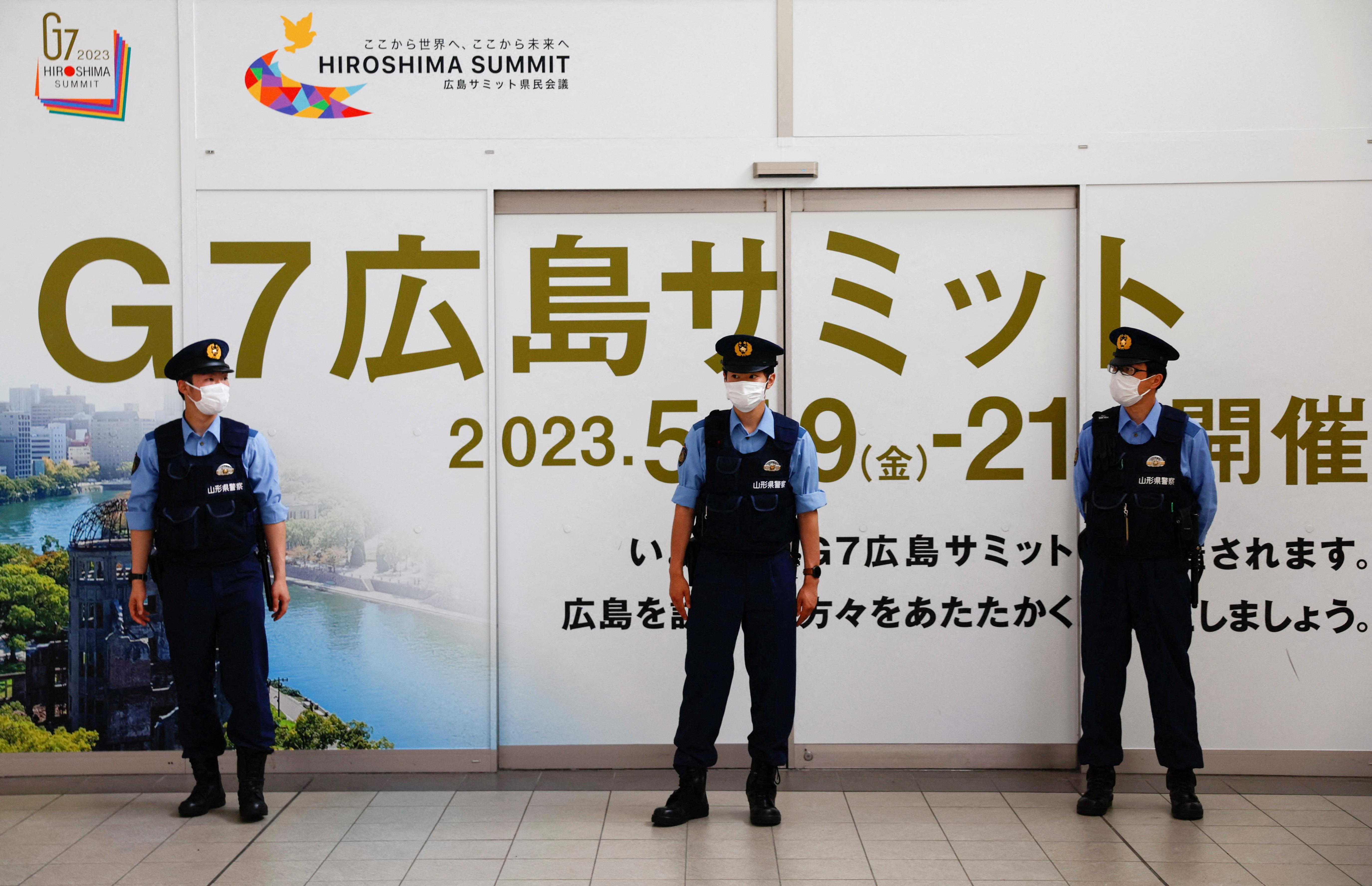 Três guardas em frente a painel do G7