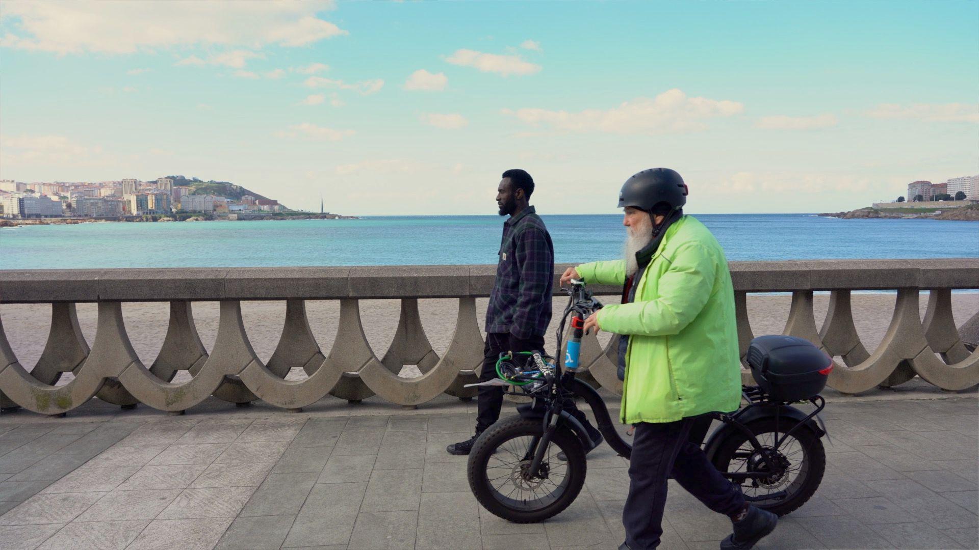 Ibrahima y Guillermo caminan por el paseo marítimo de La Coruña