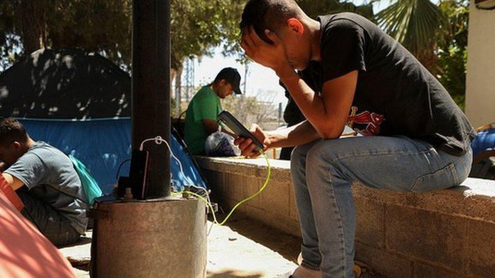 Migrante en la frontera viendo su teléfono.