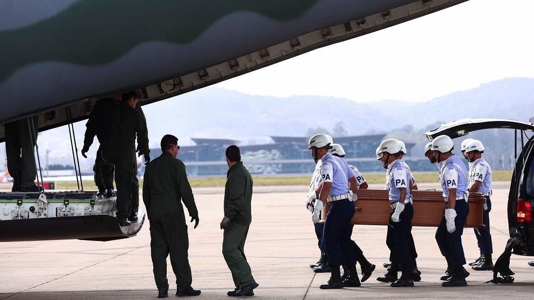 A imagem mostra seis homens da Força Aérea, carregando um caixão em direação a um avião. 