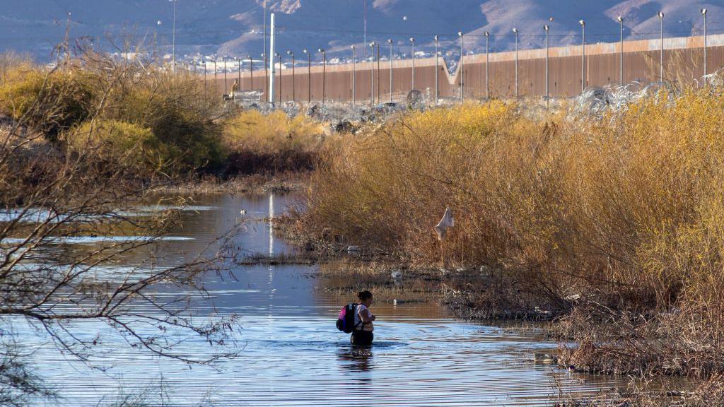 Un migrante trata de cruzar a Estados Unidos a través del río.