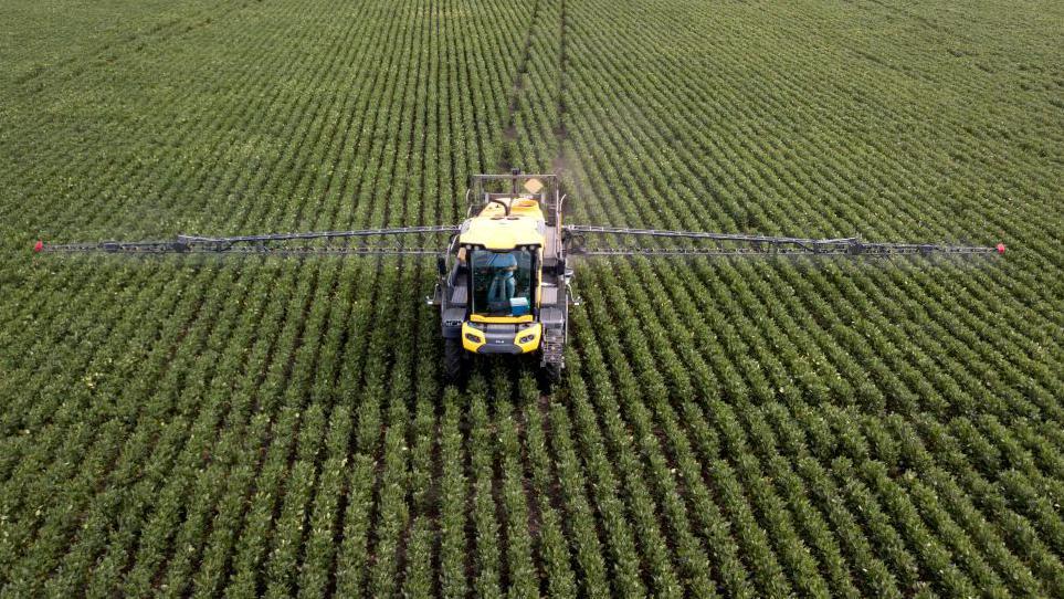Trator espalhando pesticida em campo 
