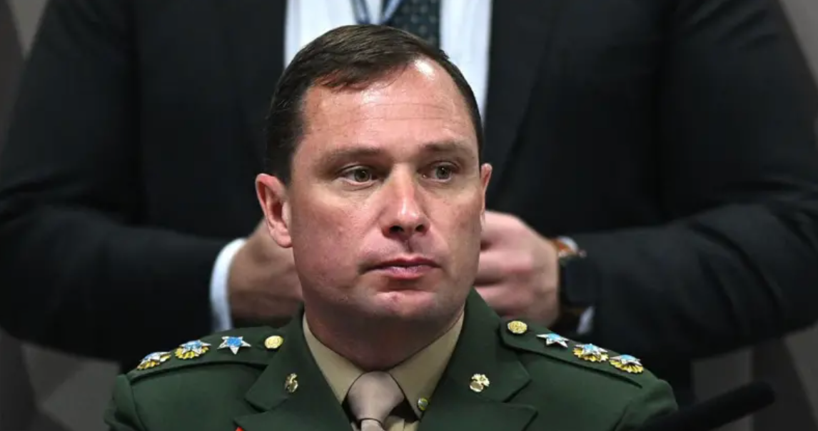 Mauro Cid usando uniforme militar em frente a um microfone durante sessão de inquérito na Câmara dos Deputados