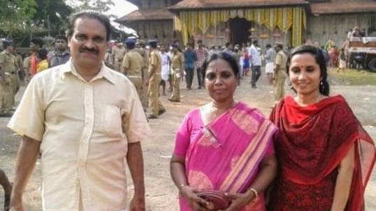 Dr Vasu standing in front of a temple. A man is standing to her rightand a young lady to her right 