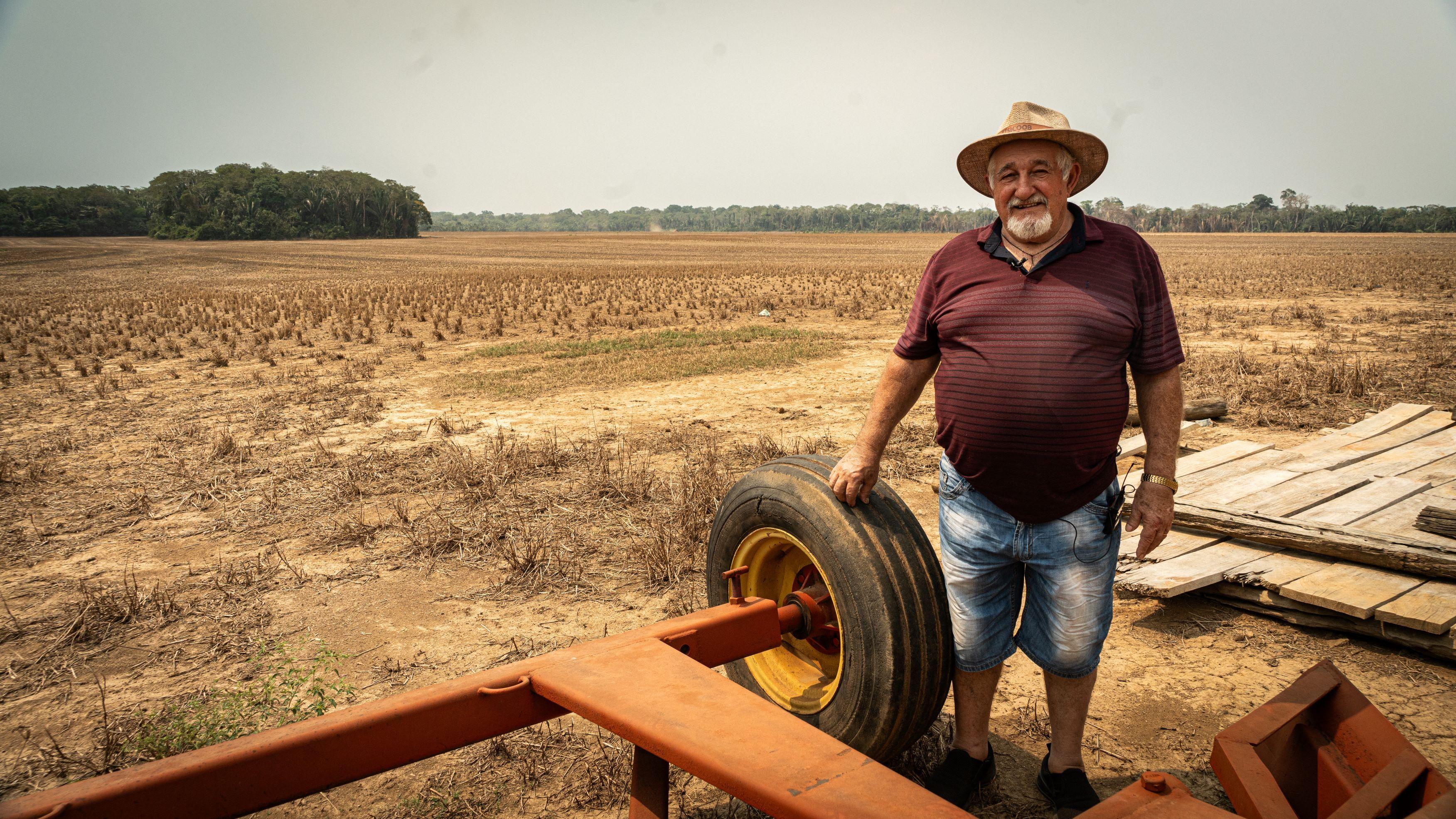 Dorismar Luiz Baruffi próximo a veículo, aparentemente um trator, com área desmatada atrás