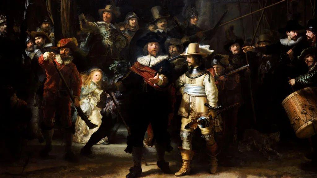 Foto mostra a pintura 'A Ronda Noturna', formada por um grupo de pessoas em movimento. No primeiro plano, um homem vestido de capitão, com um manto vermelho e uma faixa preta. Ao seu lado, um homem vestido de maneira igual, só que com roupas claras. 