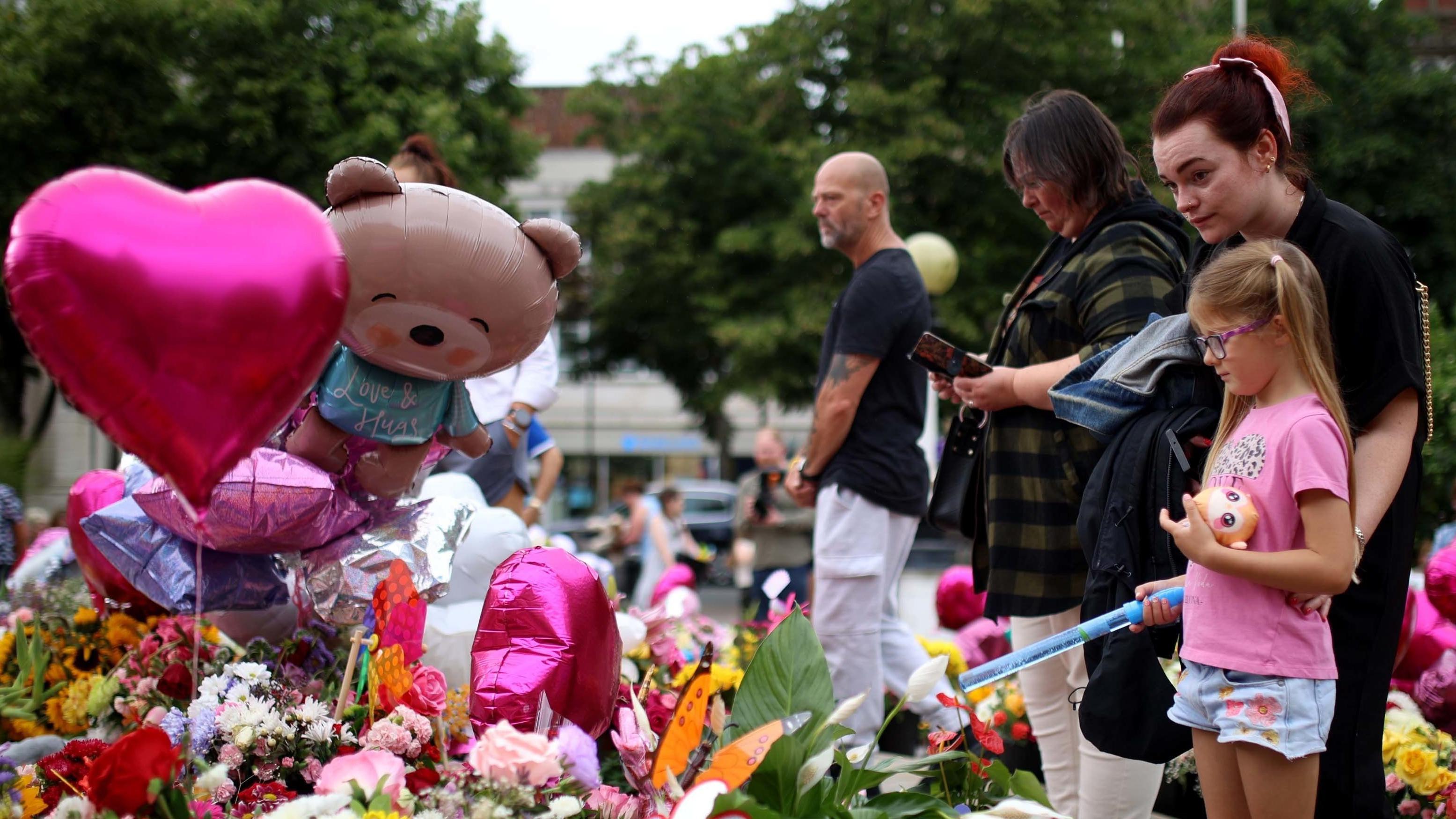 A young girl and a woman attend a vigil in Southport