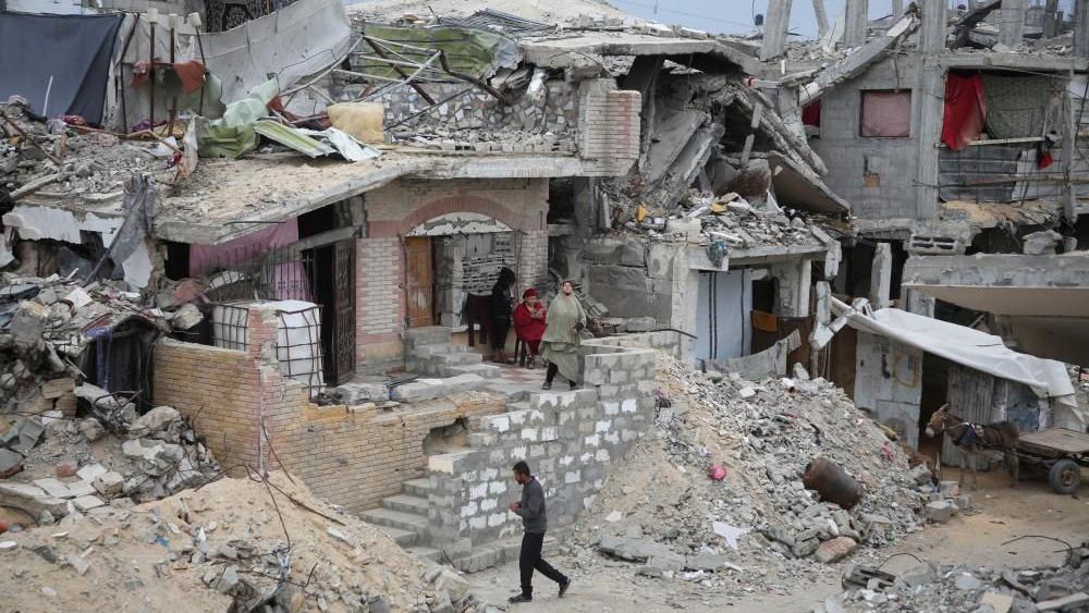 Pessoas andando por destroços e destruíram edifícios 