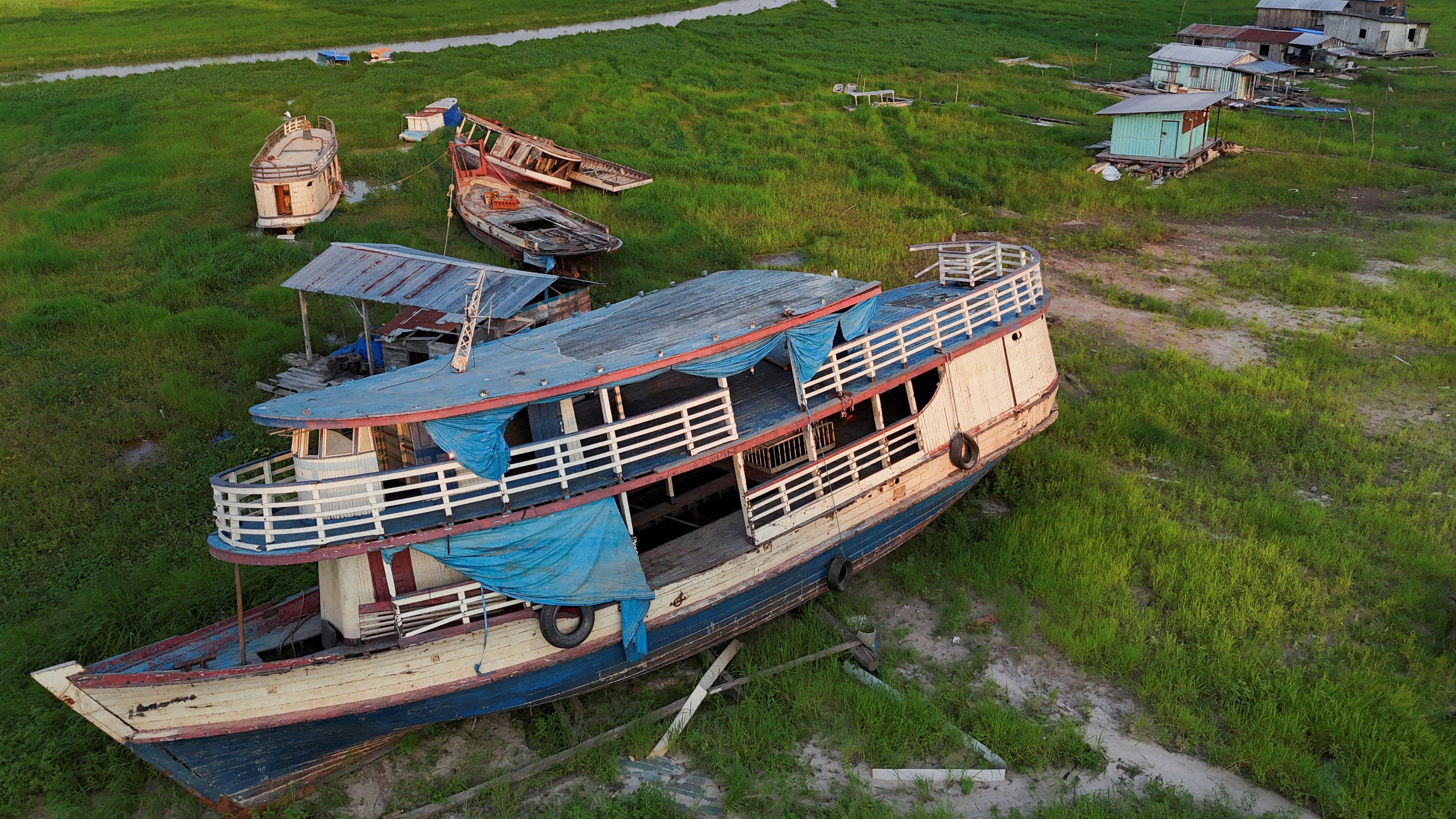 A foto mostra um barco em um gramado, onde havia um lago.