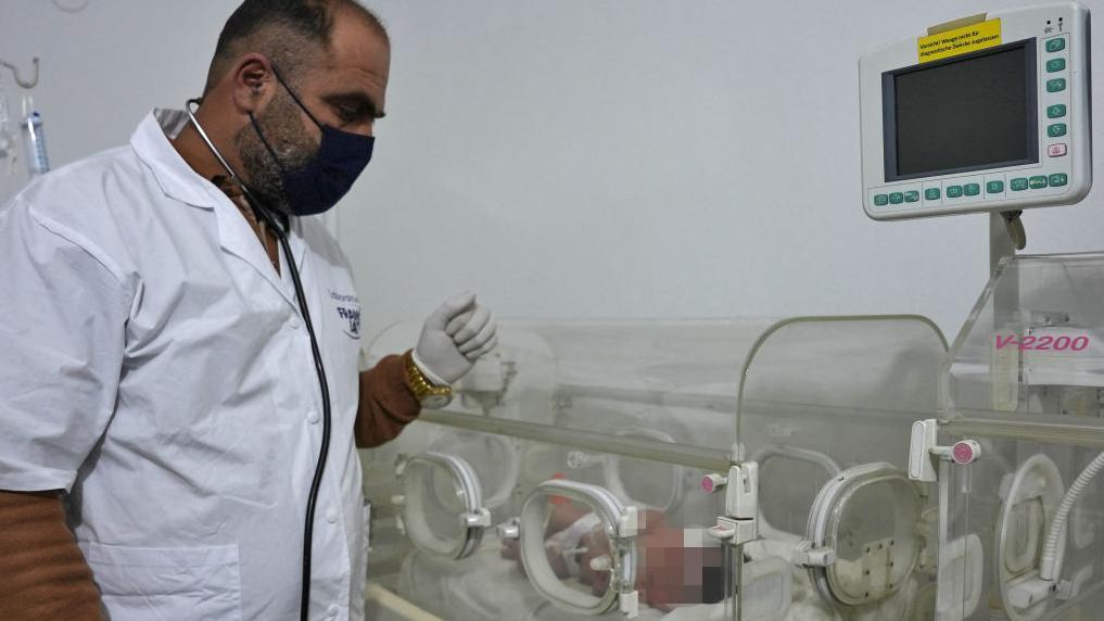 Médico olhando para bebê na incubadora