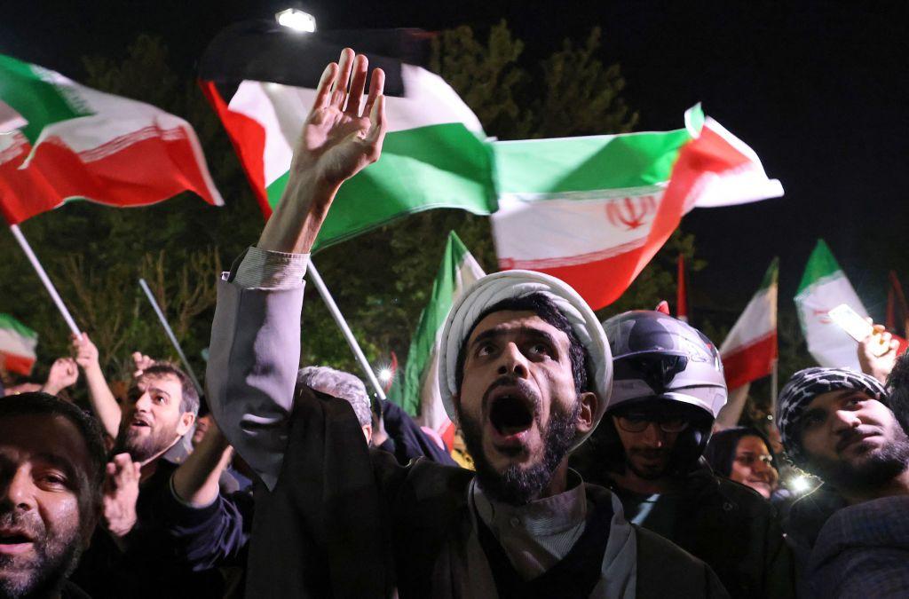 متظاهرون يلوحون بالعلم الإيراني والأعلام الفلسطينية أثناء تجمعهم أمام السفارة البريطانية في طهران في 14 أبريل/نيسان 2024، بعد أن شنت إيران هجوماً بالطائرات المُسيرة والصواريخ على إسرائيل.