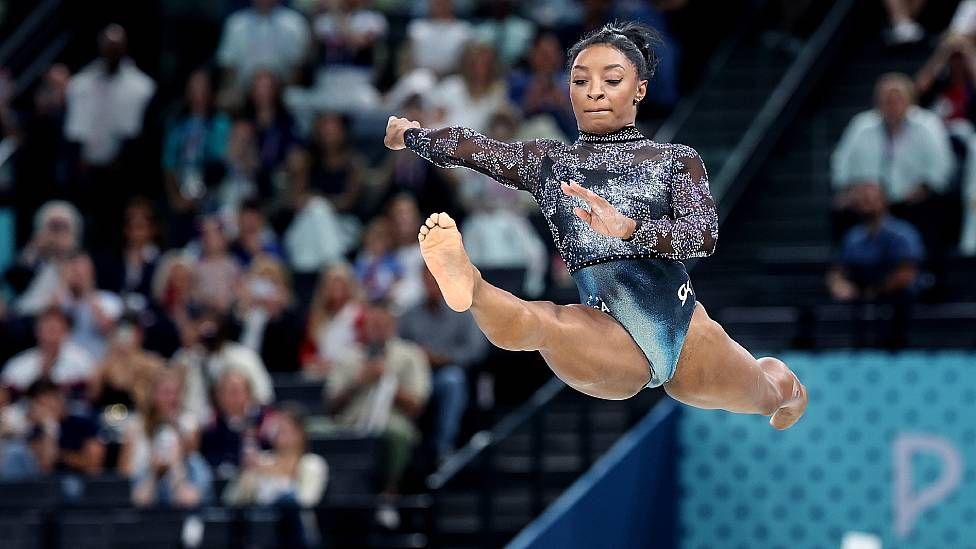 Simone Biles salta com as pernas abertas