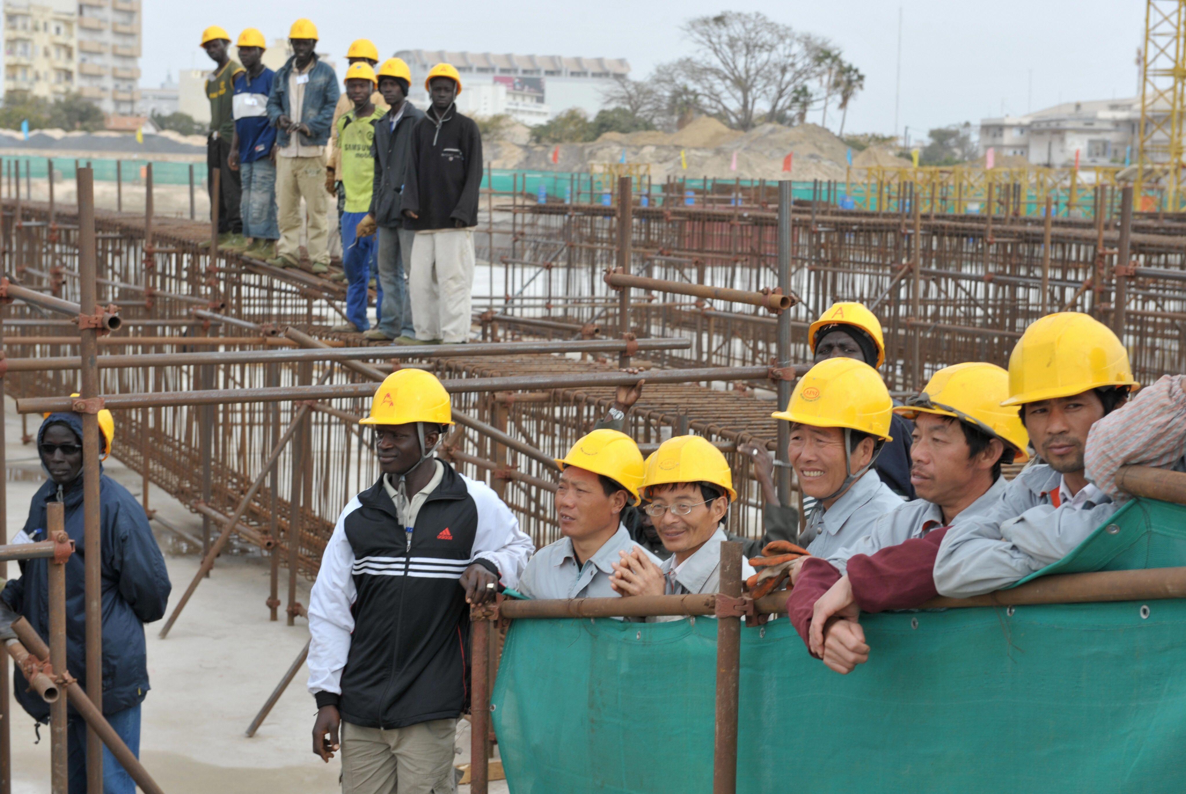 Trabalhadores chineses e senegaleses no local do Teatro Nacional parcialmente construído no Senegal