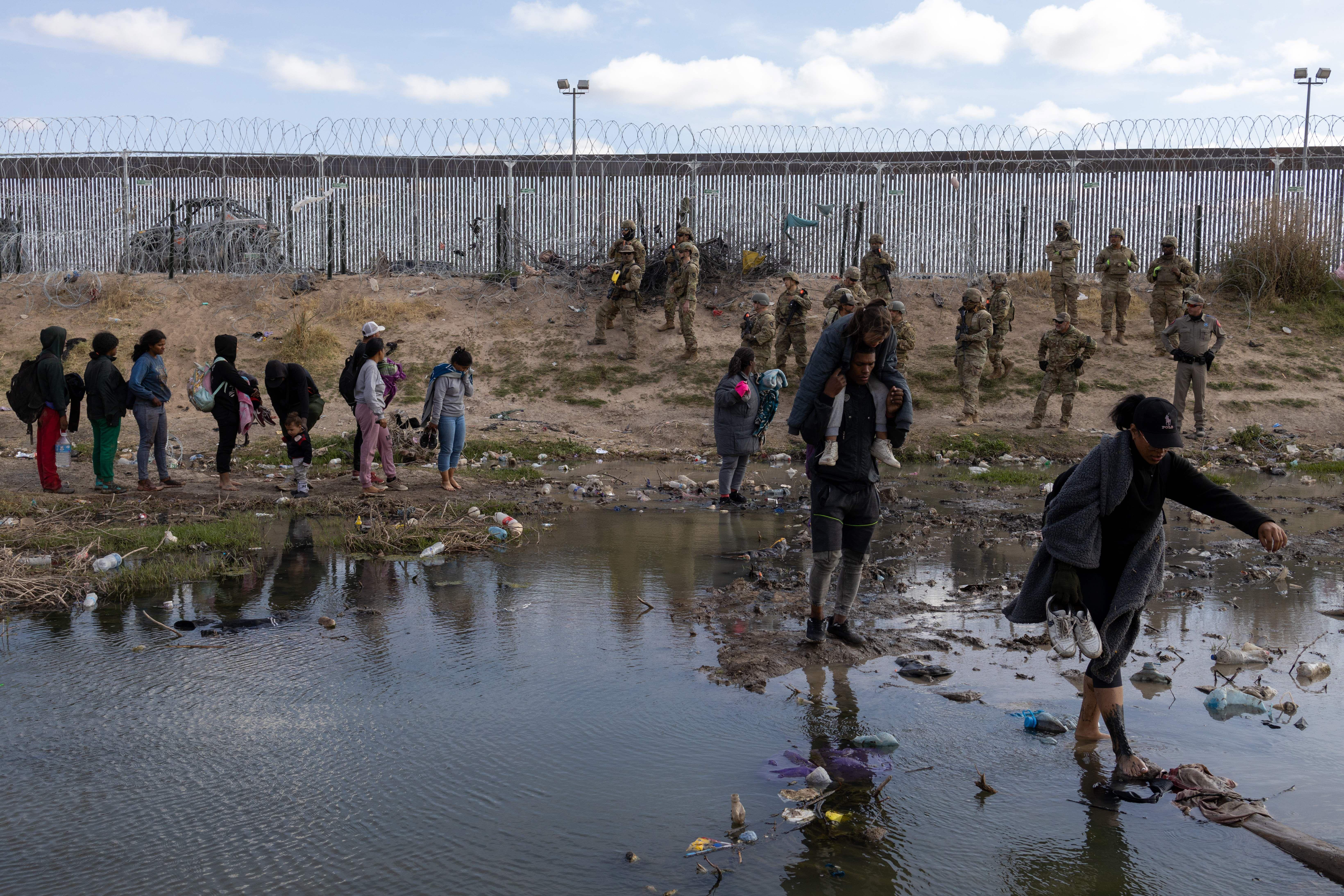 Migrants at the US-Mexico border watched by members of the Texas National Guard