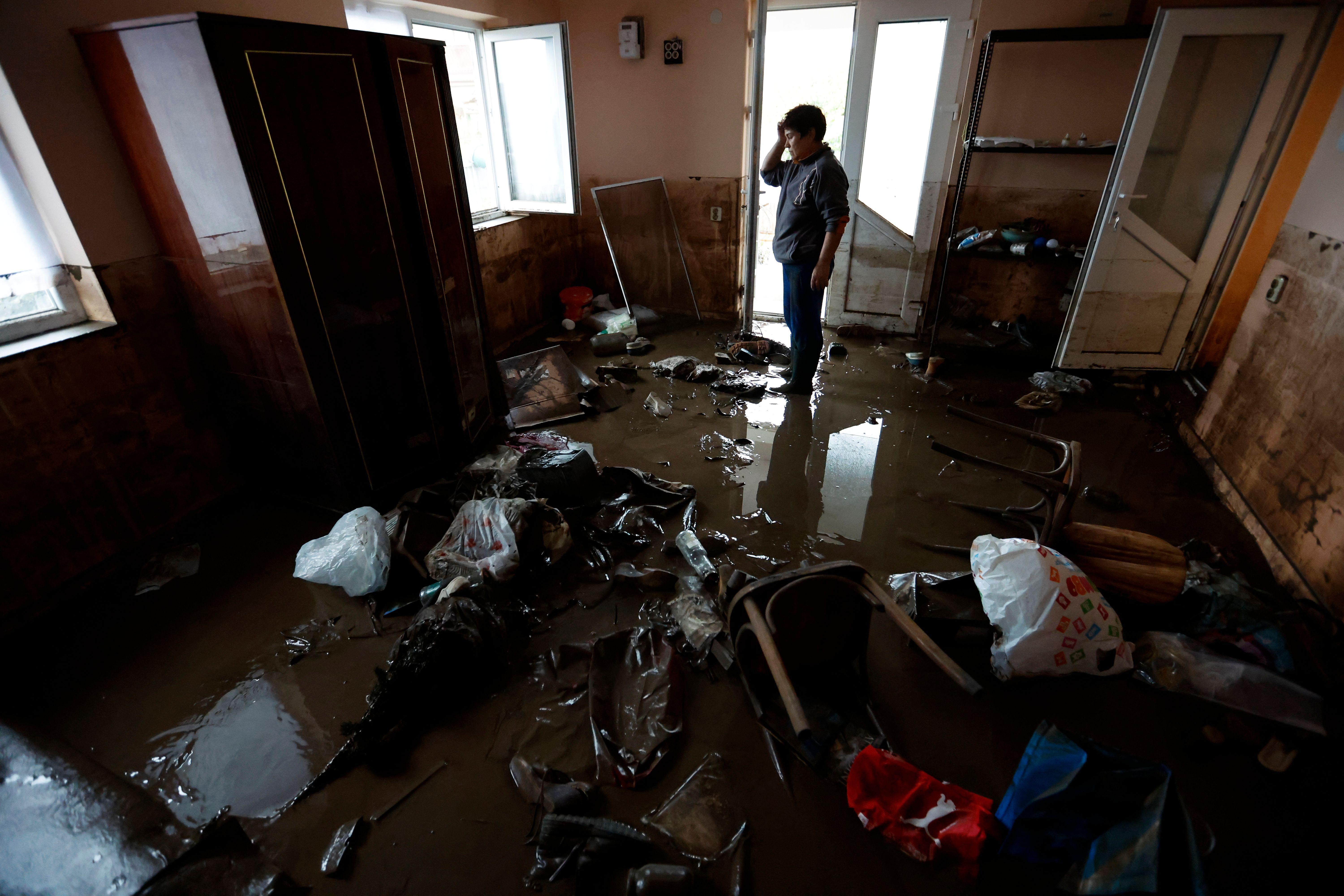 Uma mulher observa objetos que restaram após inundação de sua sala de estar na vila de Pechea, perto da cidade de Galati, Romênia