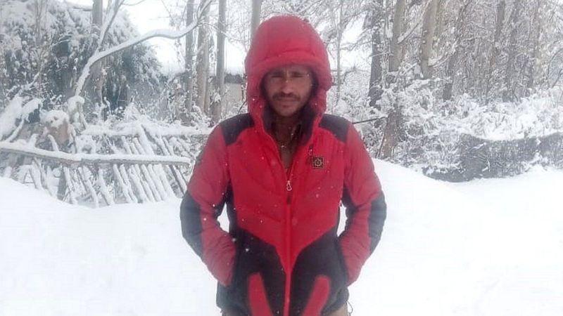 Mohammed Hassan em foto tirada na neve, usando casaco vermelho e com as mãos nos bolsos