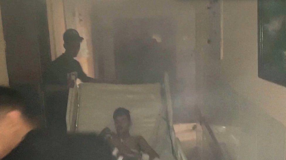 Los médicos trasladan a un paciente por un pasillo lleno de humo tras el ataque israelí al hospital Al-Shifa.