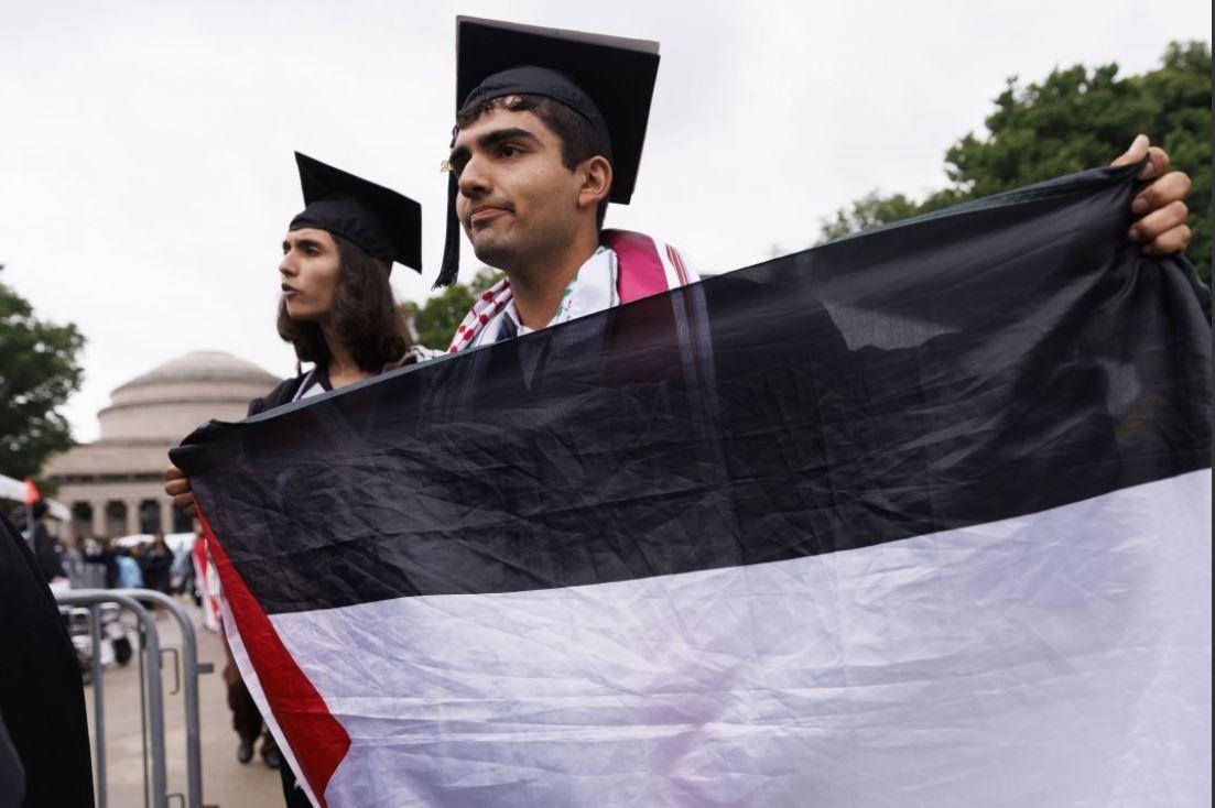 طالب يرتدي ثوب التخرج يحمل العلم الفلسطيني وطالبة ترتدي ثوب التخرج في احتجاج لإظهار الدعم لفلسطين خلال احتفالات التخرج في معهد ماساتشوستس للتكنولوجيا في كامبريدج،