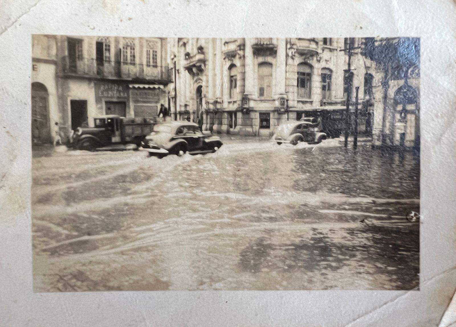 Carros passando por rua alagada