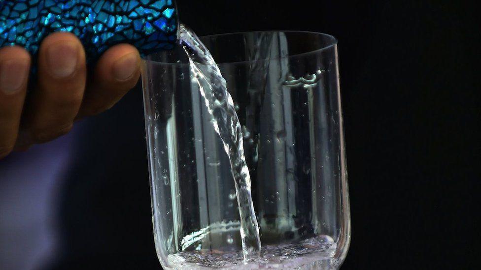 Garrafa luxuosa servindo água em taça