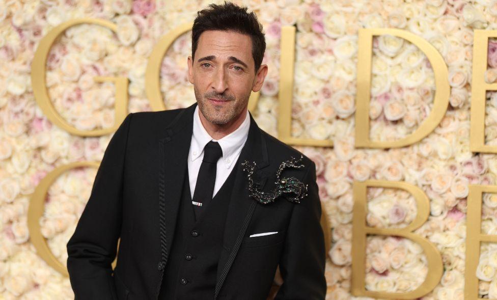 Adrien Brody em terno preto e camisa branca