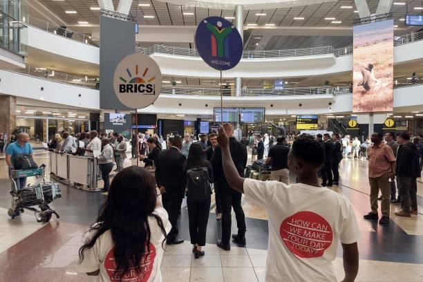 متطوعون يحملون لافتات كتب عليها بريكس في استقبال ضيوف القمة في مطار أور تامبو الدولي