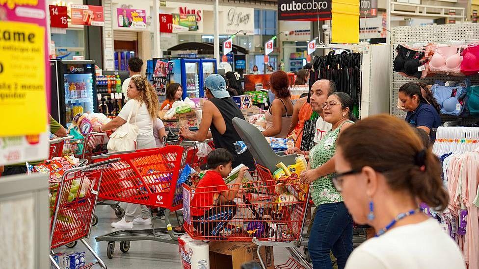 Gente en un supermercado con sus carros de compras llenos