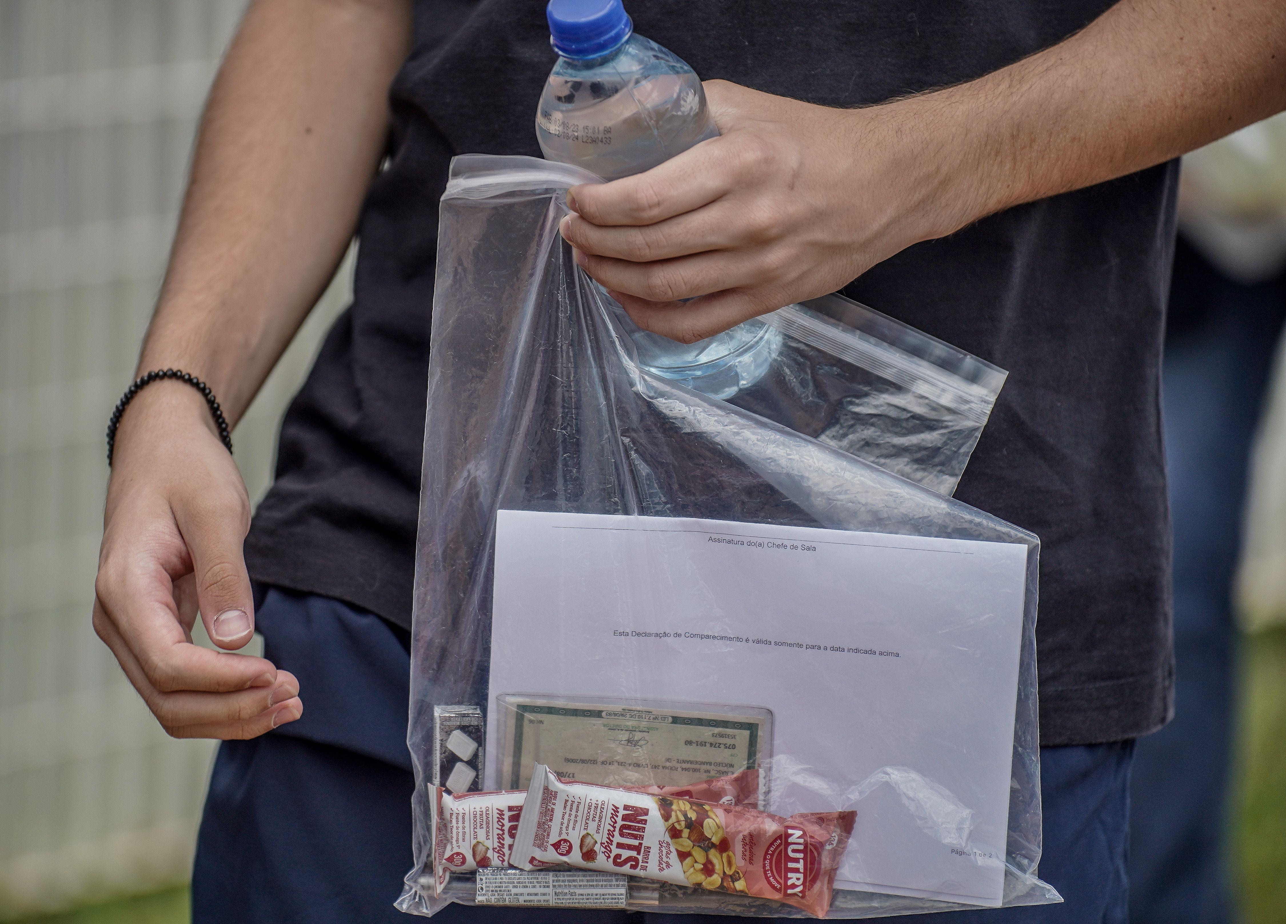 Estudantes carrega saco plástico com alimentos e documentos 