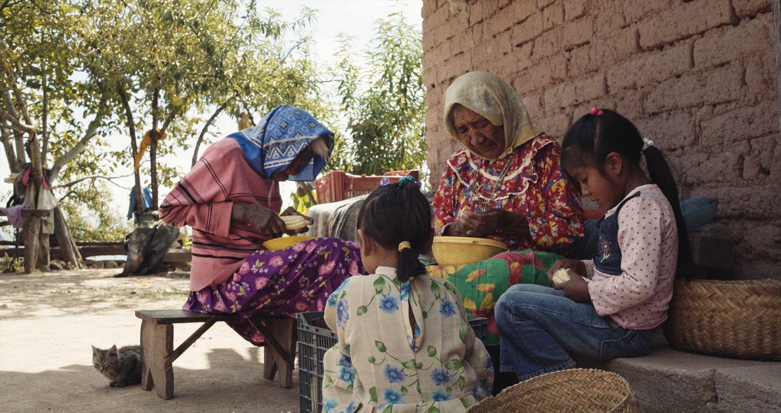 Rita deshoja una mazorca de maíz junto a su cuñada y unas niñas