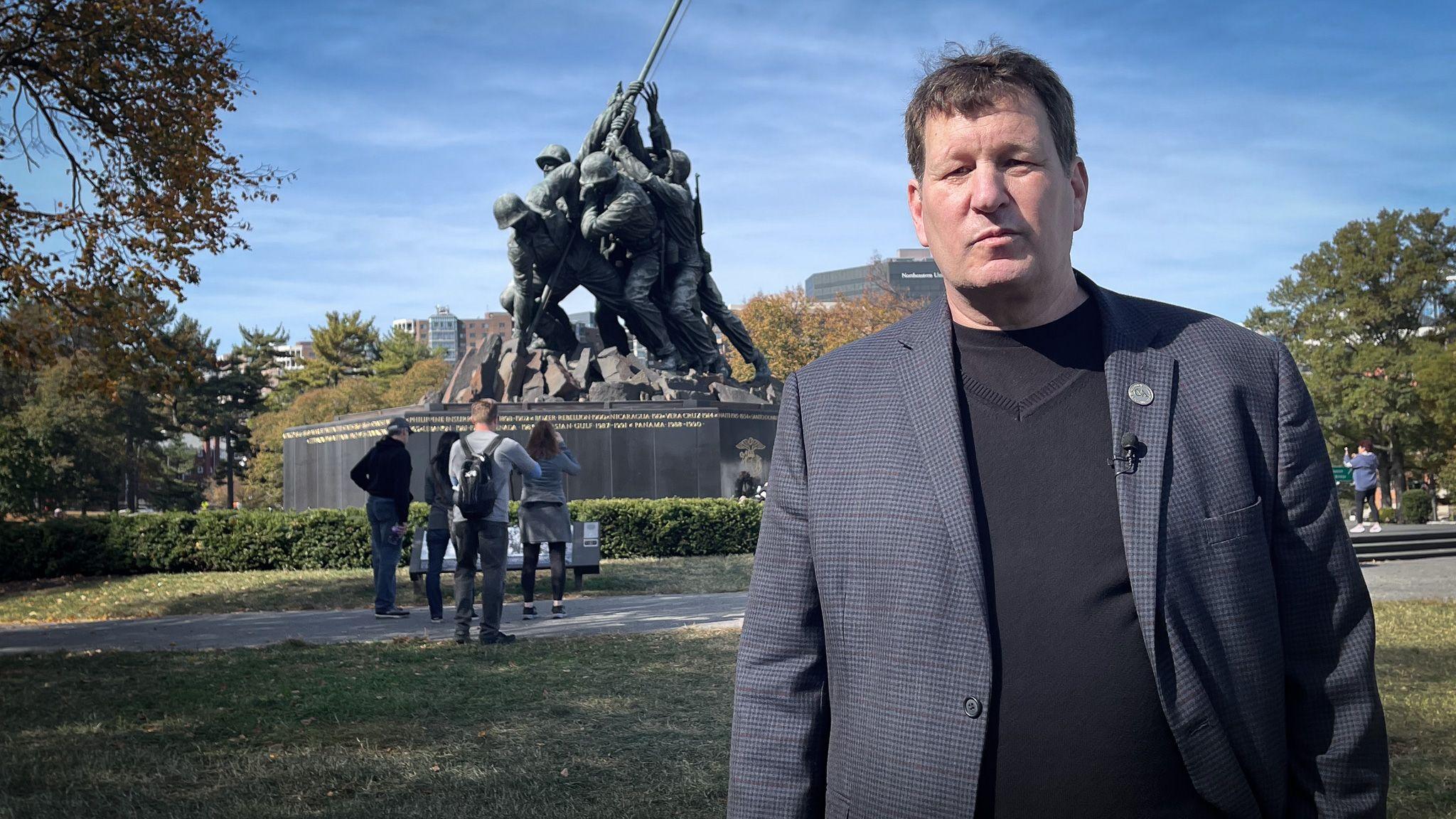 John Byrnes - um homem de blazer, em frente ao memorial dos fuzileiros navais dos EUA