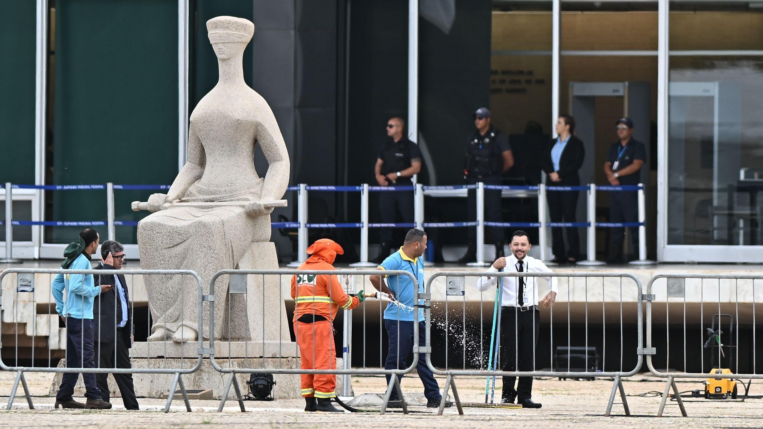 Funcionários do serviço de limpeza de Brasília limpam área da praça dos Três Poderes perto do STF, onde homem se explodiu na quarta-feira.