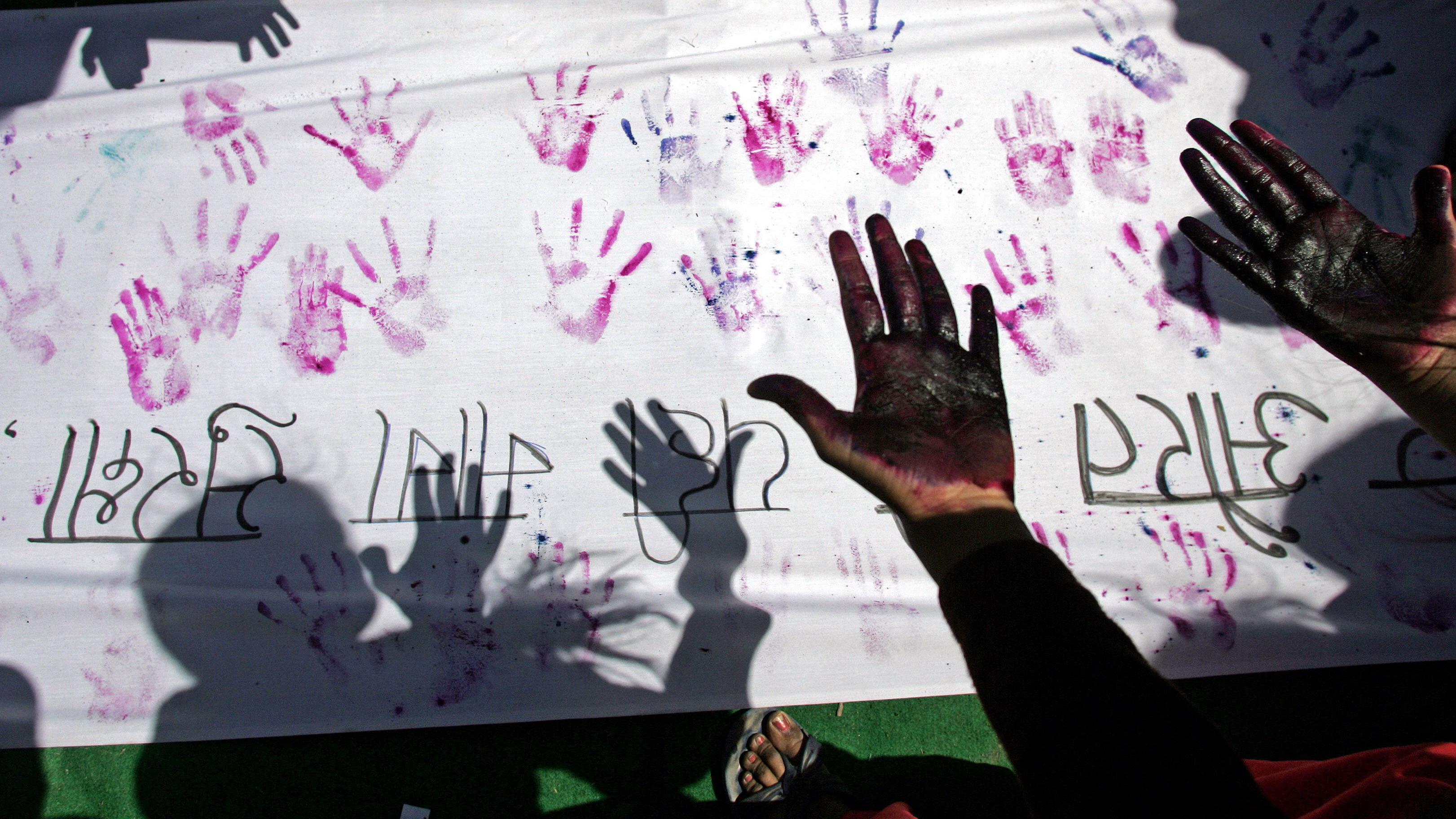 Foto de arquivo de uma mulher indiana olhando para suas mãos após fazer uma impressão de mão em uma faixa durante uma marcha de rua contra o assédio sexual e a violência conjugal para marcar o Dia Internacional da Mulher em Nova Déli