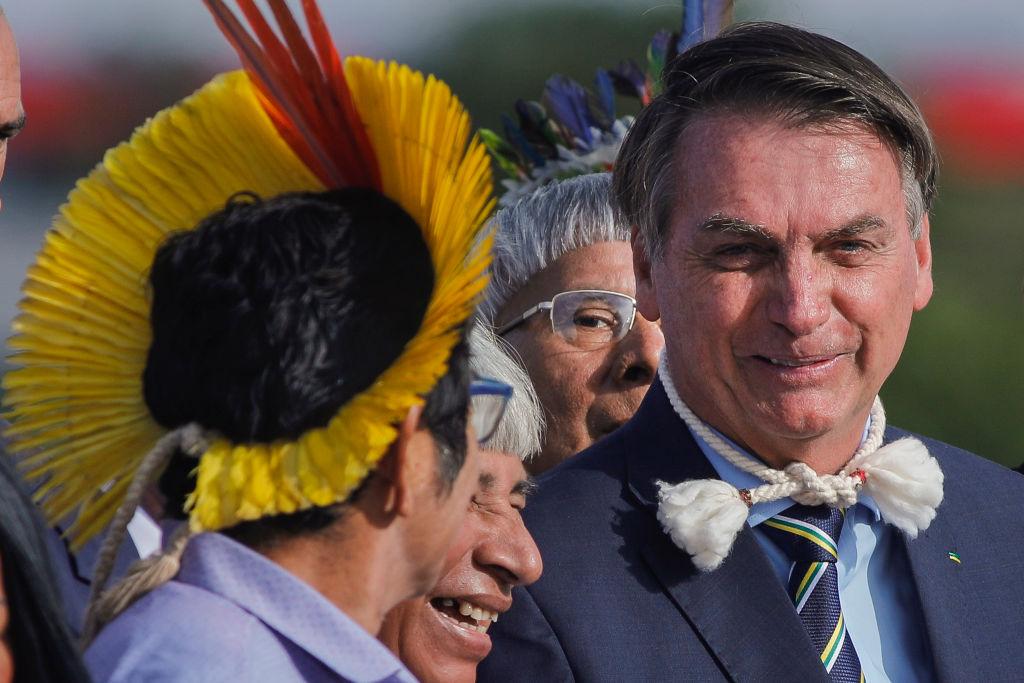 Bolsonaro sorrindo e conversando com três indígenas