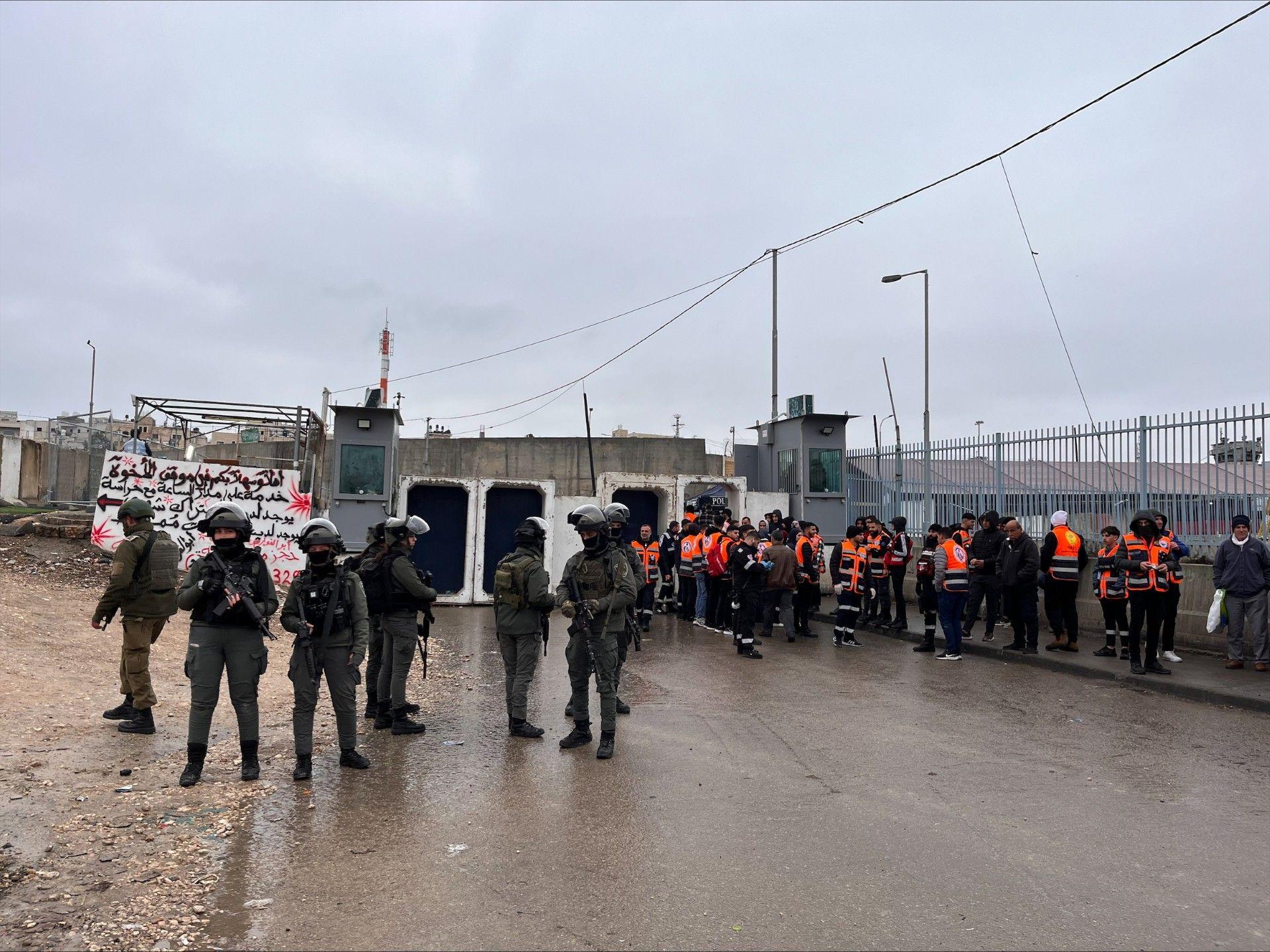 قوات إسرائيلية عند حاجز تفتيش قبل السماح بدخول فلسطينيين للصلاة في باحات المسجد الأقصى. السماء غائمة والأرض مبتلة.