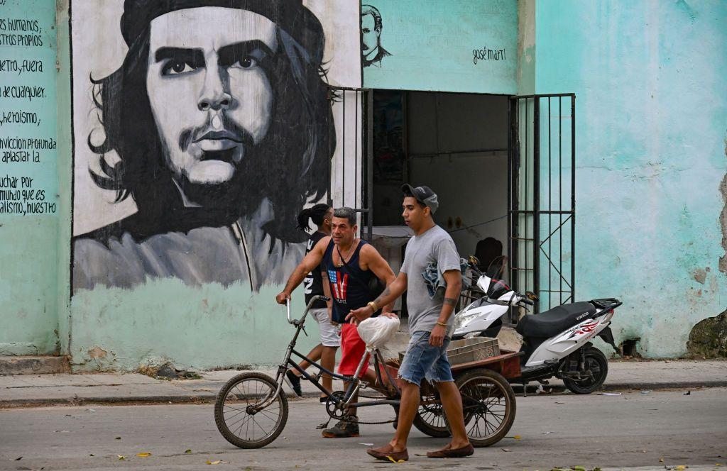 Dos personas empujan un triciclo bajo un retrato del "Che" Guevara en una calle de La Habana. 