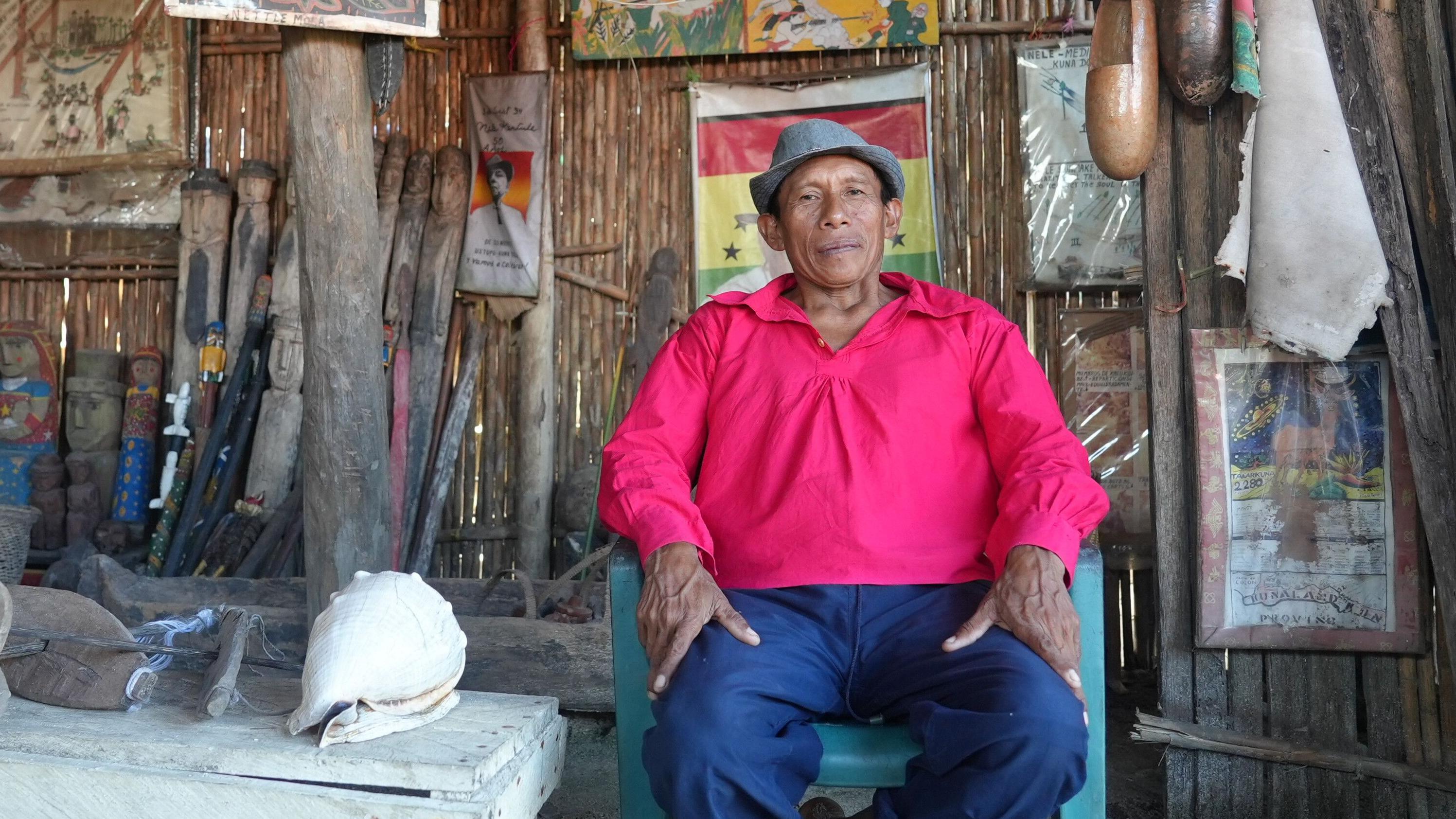 Delfino posa junto al pequeño museo donde tiene herramientas e instrumentos gunas