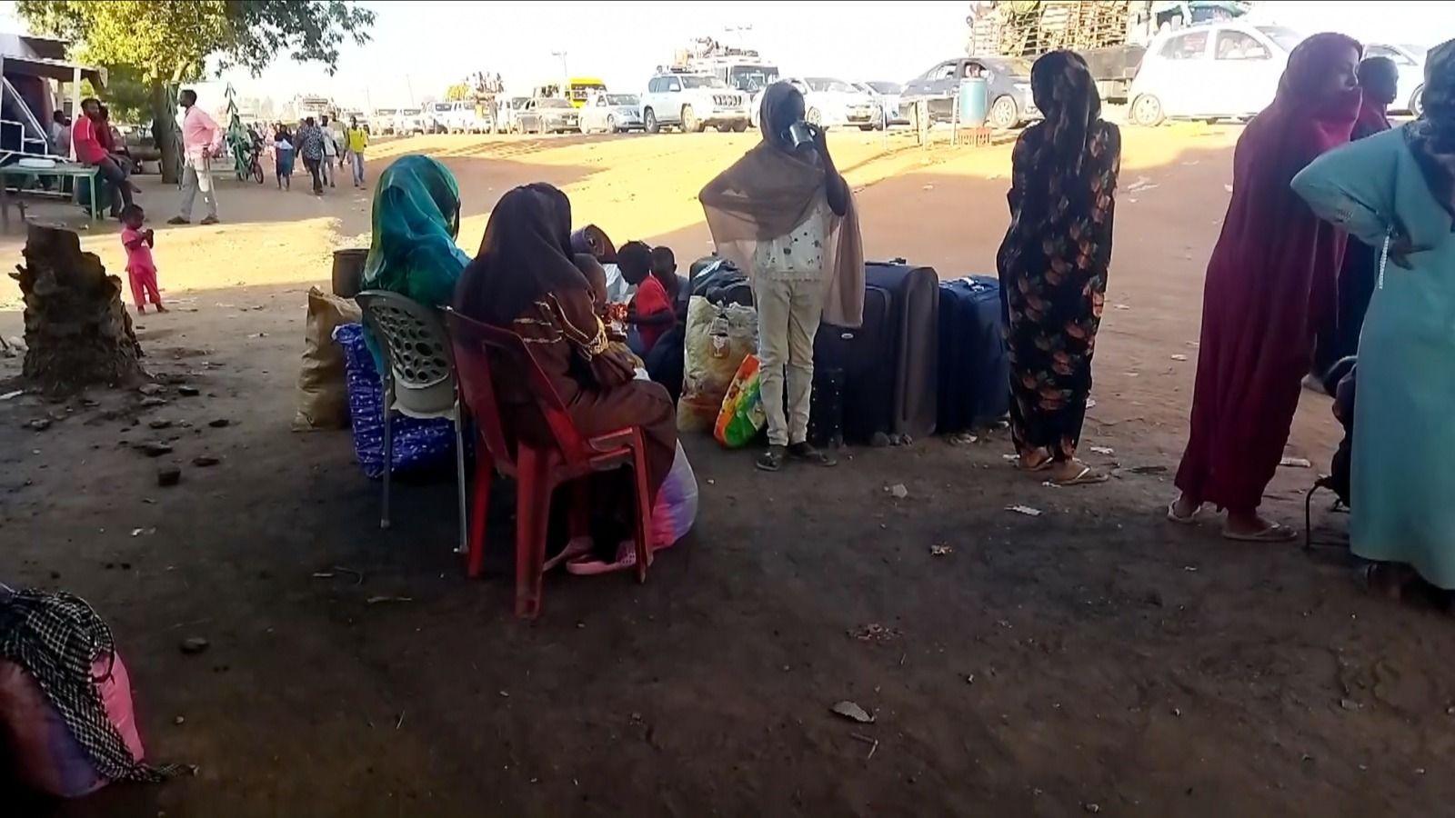 Um grupo de mulheres em pé e sentadas à beira da estrada.