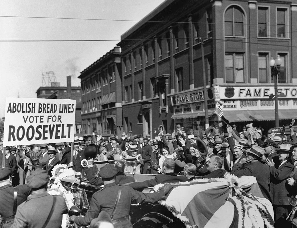 El entonces candidato a la presidencia Franklin Delano Roosevelt en un rally de campaña en Indianápolis en 1932 y un cartel que dice "Abolir las filas por pan. Vote por Roosevelt".