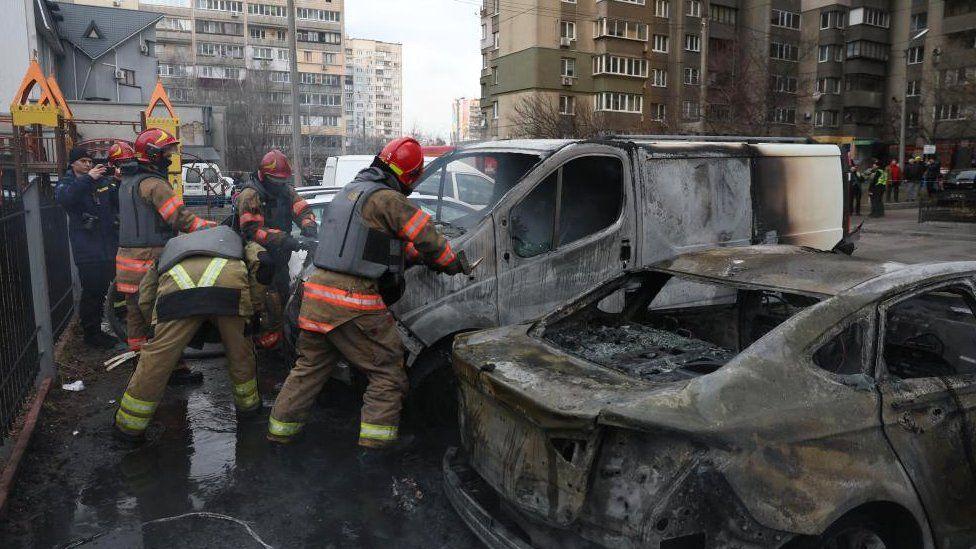 Equipes de emergência diante de carros em chamas danificados pelos ataques de mísseis russos em Kiev