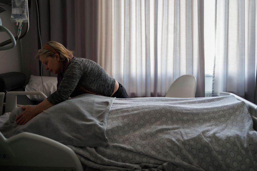 Una mujer se inclina sobre una cama de hospital.