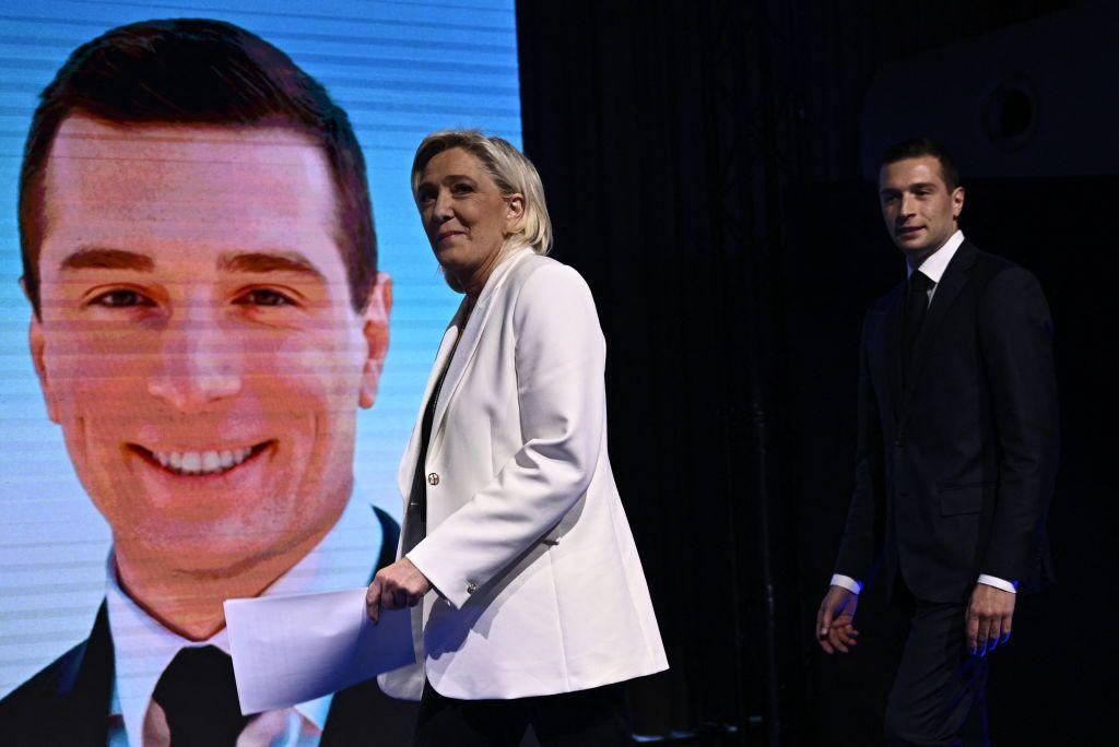 Marine Le Pen e Jordan Bardella andando no palco