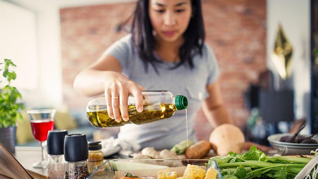 Una mujer echándole aceite de oliva a la ensalada