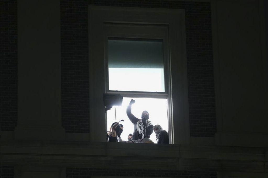 Manifestante en una ventana del edificio con el puño en alto.
