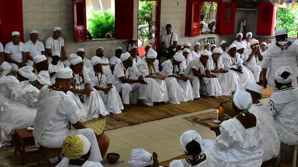 Pessoas de branco reunidas e sentadas