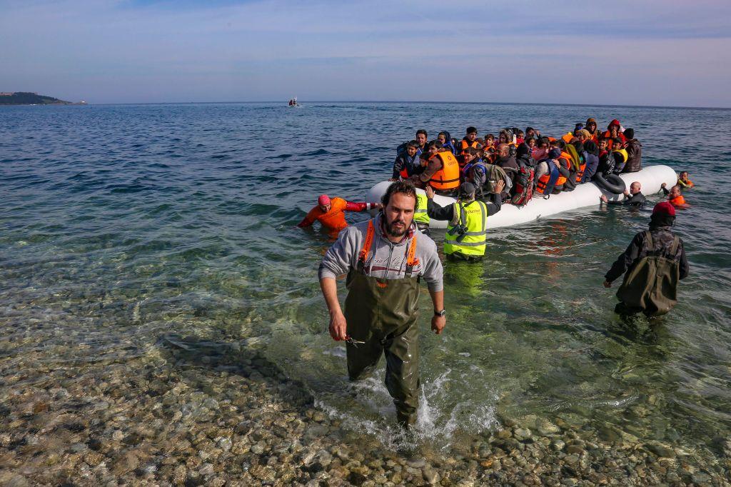 Deniz kıyısı, görevliler bir botta oturan insanları sahile çekiyor