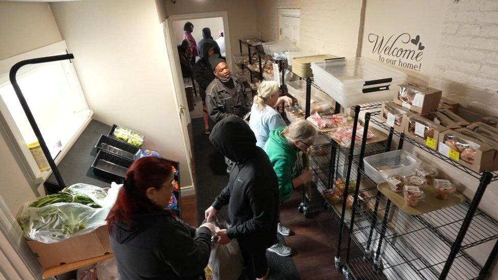 Vecinos de Erie reciben bolsas de comida en un banco de alimentos. 