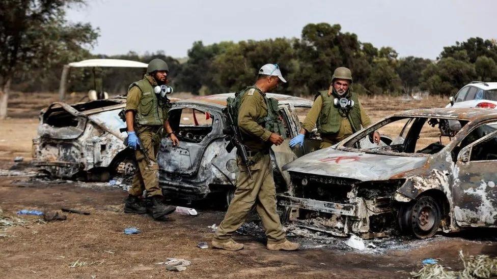 Soldados israelenses circulam em meio a carros queimados