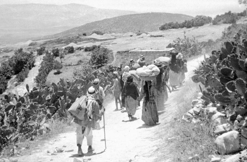 Palestinos carregam pertences em paisagem semidesértica