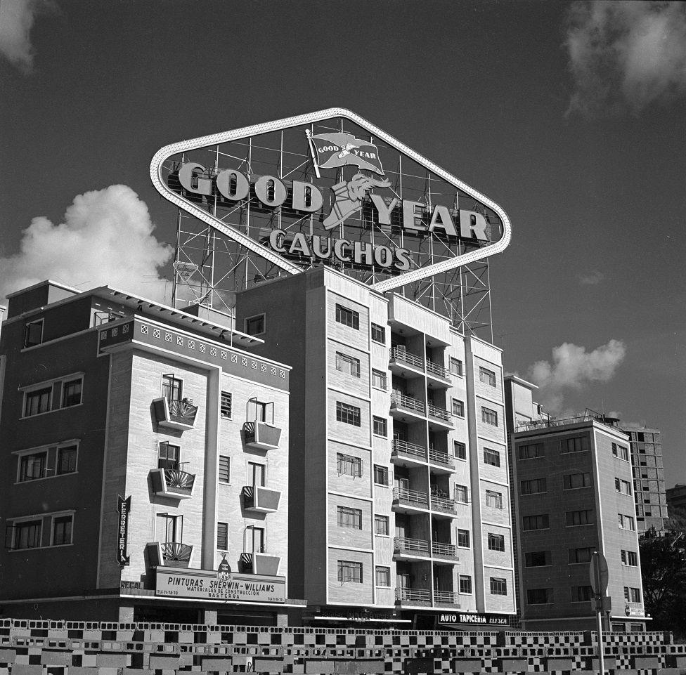 Un edificio de apartamentos con una publicidad que dice: Good Year. Cauchos