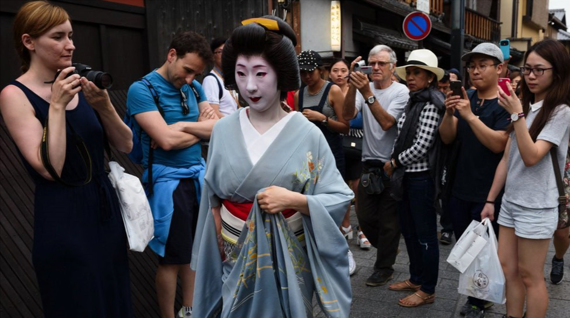 Tourists take photographs of a geiko walking through the Gion area of Kyoto, Japan, on Thursday, May 28, 2015.